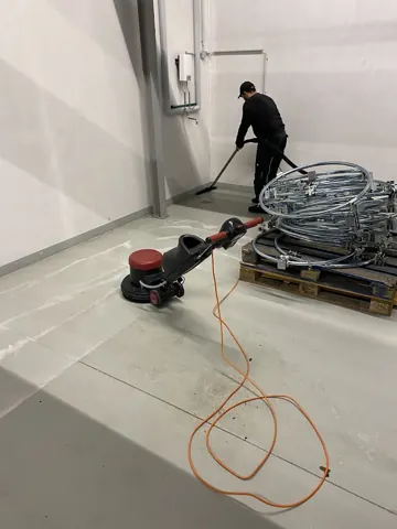 Maschinelle Reinigung einer Bodenfläche neben Baumaterial